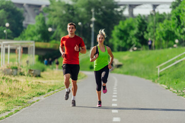 Full-length front view of an attractive caucasian couple running together in a park on a sunny day..