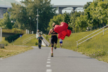Obraz premium View from the back of a young female athlete running with a parachute in the park