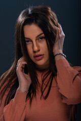 Obraz premium Close up portrait of beautiful young female model with orange blouse on black background
