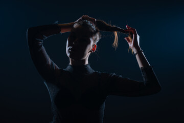 Dark contrast portrait of beautiful young woman with ponytail hairstyle