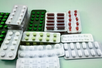 Blister of mix pills, vitamins, tablet, medicine  on  green background. Convolute pills, vitamins. Pharmacy