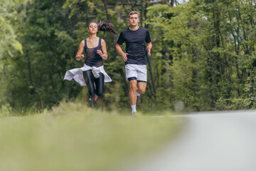 Obraz premium Young fit couple atheltes running on running road in a forest.