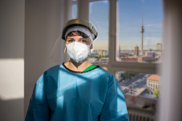 Covid-19 female doctor with respirator and shield indoor portrait with a view of Berlin