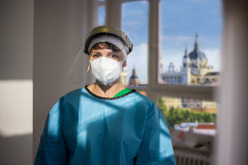 Covid-19 female doctor with respirator and shield indoor portrait with a view of Madrid