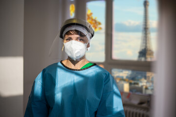Covid-19 female doctor with respirator and shield indoor portrait with a view of Paris