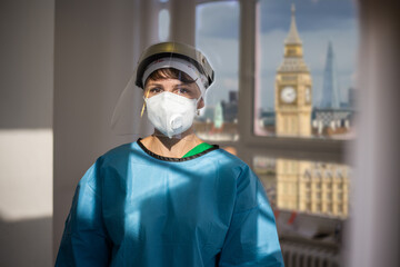 Covid-19 female doctor with respirator and shield indoor portrait with a view of London