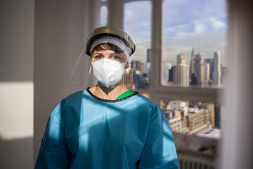 Covid-19 female doctor with respirator and shield indoor portrait with a view of New York