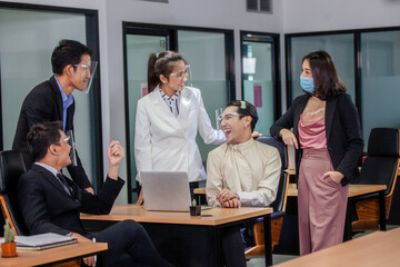Happy to work together. Group of young business people talking and smiling while standing near the wooden desk in the office. Group of colleagues working at new financial project in office
