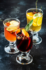 Mulled wine from red and white wine and hot mulled cider. Autumn or winter drinks and cocktails in glass mugs with spices and citrus fruit