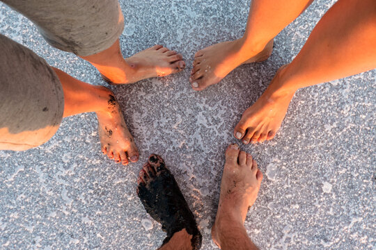 Three pairs of bare feet on the salty ground