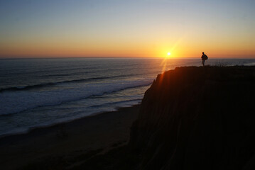 Surfer watching sunset from the bluffs
