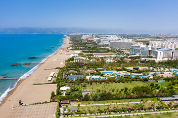 Fototapeta premium Sandy beaches of the Mediterranean. Kundu holiday complex with five star hotels. Beach, sea, water sports, parasailing, entertainment and shopping center. Aerial view with drone. Kundu, Lara -TURKEY