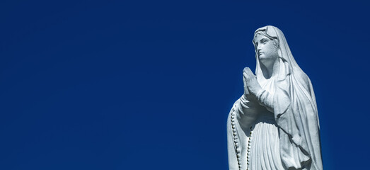 Close up ancient statue of the Virgin Mary praying. Free copy space for design.