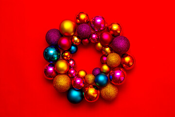 Fototapeta na wymiar Christmas colorful wreath handmade from christmas balls on a red background. New Year's interior decoration