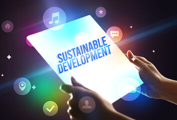 Holding futuristic tablet with SUSTAINABLE DEVELOPMENT inscription, new technology concept