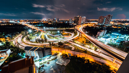 Long exposure light trail of car traffic transportation on highway road intersection in Bangkok city Thailand, cityscape high angle view at night. Public transport, Asian city life concept