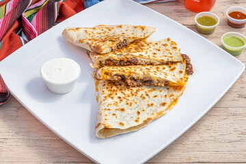 Mexican cheesy quesadilla made with Monterey jack cheese and marinated chicken. Made by melting cheese inside of a large flour tortilla.