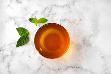 Top view of glass cup with tea on white marble background
