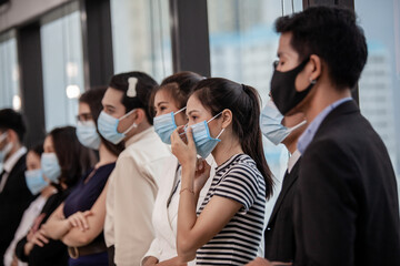 Young people with face masks at work in office. Group of bussiness with face masks looking at camera, corona virus concept.