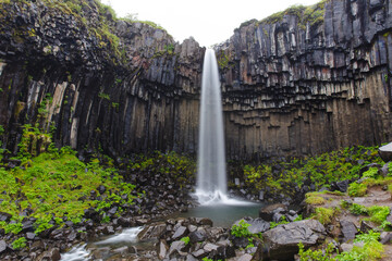 small waterfall in the middle of basalt rock columns 