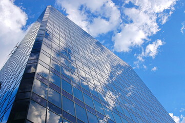 Cloud filled sky reflected on an office building.