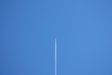 white trail of a plane far away in the blue sky