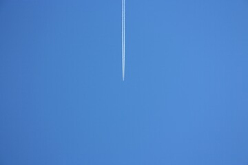 white trail of a plane far away in the blue sky