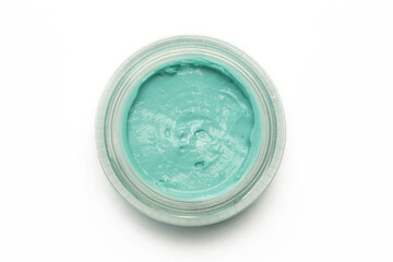 Green clay facial mask in container isolated on white background, top view