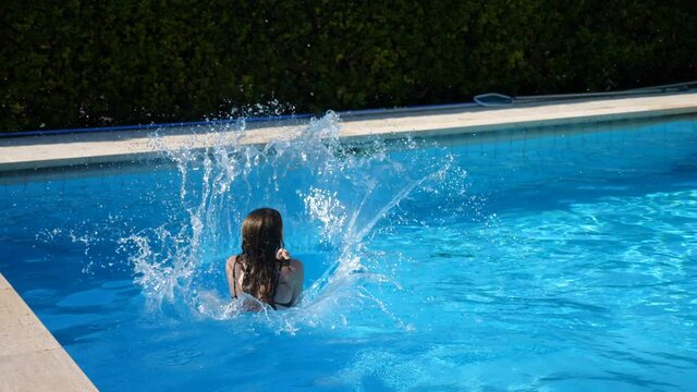 fun, holidays - young woman  running and doing a cannonball in the pool