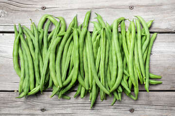 Many green bean pods on aged wood bench. Beautiful top view arrangement of  home grown blue lake...