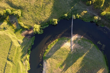 Suspension bridge over a small river, aerial view. Hanging bridge across river. Summer landscape