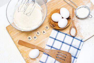 making dough for bread or homemade baked goods. ingredients on a wooden table. inscription: bread