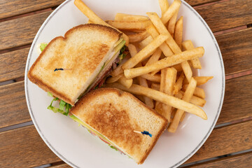 Club sandwich and french fries on a plate makes a delicious meal when hungry.