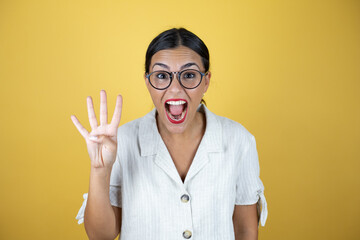 Beautiful woman over yellow background showing and pointing up with fingers number four while smiling confident and happy.