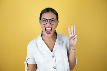 Beautiful woman over yellow background showing and pointing up with fingers number three while smiling confident and happy.