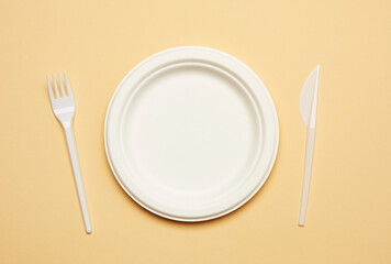 empty round brown disposable plate made from recycled materials  on a beige background