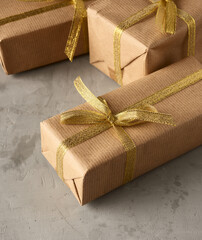 rectangular box wrapped in brown paper and tied with a silk ribbon with a bow, gift on a gray...