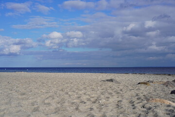 Fototapeta na wymiar Sandstrand, blaues Meer, blauer Himmel, weiße Wolken und Sonnenschein