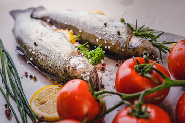 fresh rainbow fish trout on black stone background with vegetables 