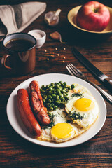 Breakfast with fried eggs, sausages and green peas