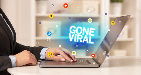 Freelance woman using laptop with GONE VIRAL inscription, Social media concept