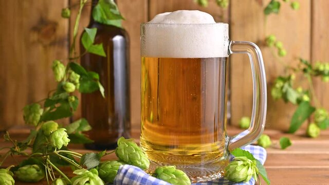 Beer. Cold Craft light Beer in a glass with water drops. Pint of Beer close up on a wooden background. Beer is pouring from the bottle. Border design. High quality 4k footage