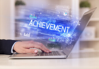 Closeup of businessman hands working on laptop with ACHIEVEMENT inscription, succesfull business concept