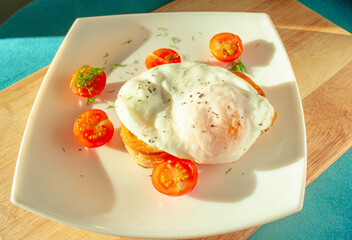 sunny morning breakfast on white plate. tomatoes with fried eggs on toast