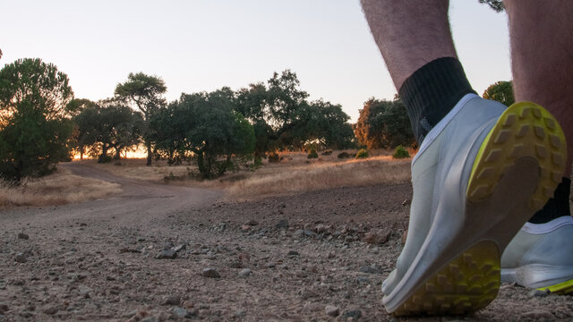 Senderimo con zapatillas de deporte en el campo con atardecer