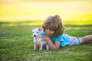 Child lovely embraces his pet doggy. Kid boy with dog relaxing on nature.