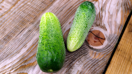 Cucumbers lie on a wooden Board. Two ripe green cucumbers. Vegetables close-up.