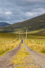Lone Walker on Deserted Rural Mountain Road (Boreen) in Ireland in Evening Sunlight