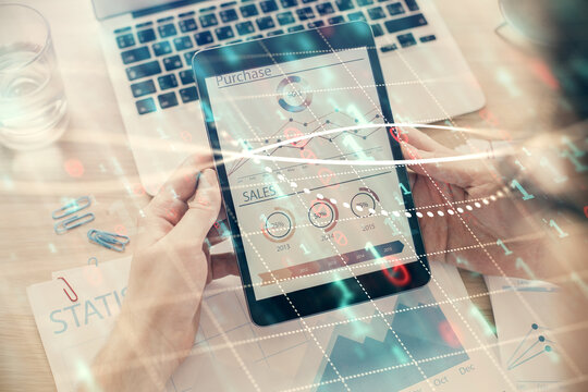 Double exposure of man's hands holding and using a digital device and forex graph drawing. Financial market concept.
