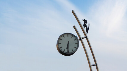 City clock on the street on a sunny day with the figure of a cat